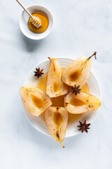 A plate of poached pears topped with sweet honey and garnished with star anise.