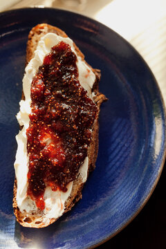 Slice of walnut bread spread with butter and fig jam