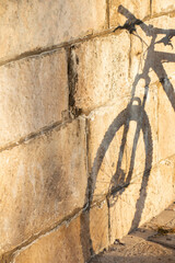 Shadow on a stone wall  of a parked bicycle on a pier - 447569458