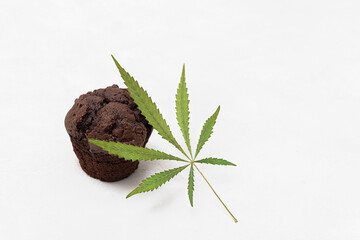 Baking with cannabis concept. Brownie cupcake with cannabis leaf in neutral background with copy...