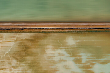 Abstract aerial view of blue-green water in shifting red deposition of sediment gradually moving through alluvial plains of Francois Peron National Park in Western Australia.