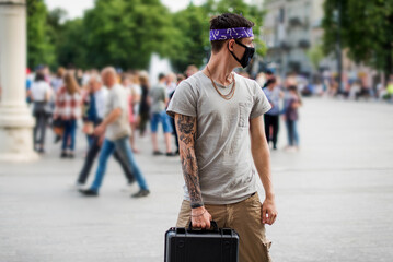 Positive man wit dressed in street style clothes with chains around neck, violet bandana and black...