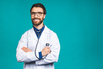 Portrait young bearded doctor with stethoscope over neck in medical coat standing against isolated blue background.