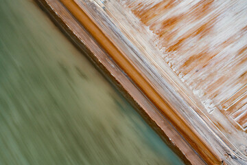 Abstract aerial view of blue-green water in shifting red deposition of sediment gradually moving through alluvial plains of Francois Peron National Park in Western Australia.