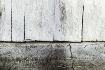 textured old wood board with white paint residues and and a part of a concrete wall. template for...