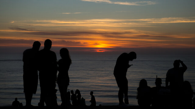 silhouettes of people on the beach at sunset