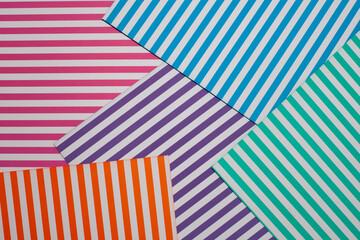 Geometric striped background. A modern, trendy multi-colored background made of sheets of striped paper lying in layers on top of each other.