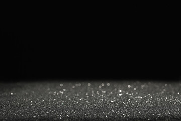 Shiny grey glitter on black background, space for text. Bokeh effect