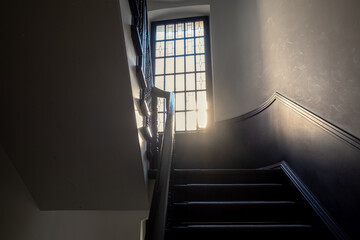 Interior view of stairway and sunlight through window.