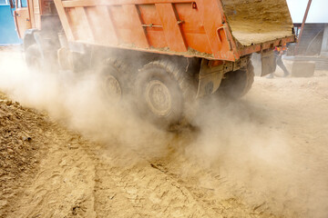 A large truck is driving on a dusty road