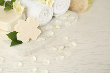 Fototapeta na wymiar Beautiful jasmine flowers, towels and soap bars on white wooden table