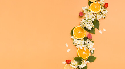 Citrus and strawberry slices with garden jasmine flowers on an orange background. Summer background...