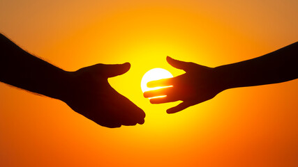 Plakat silhouette of male and female hands on the background of the setting sun. concept of communication and striving for closeness in society and family