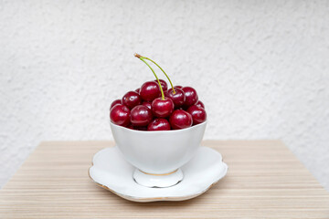 Cup of cherries on the wooden table. Fresh cherries as a healthy snack.
