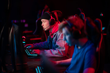 International gaming event. Arena for conducting esports competitions. Young players with headphones are playing a popular online game.