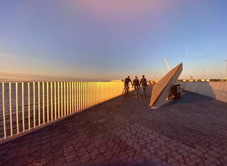 Sunset in harbor  Promenade pier  sea water wave reflection people walk and relax modern urban  architecture port of Tallinn Estonia Baltic sea  panorama