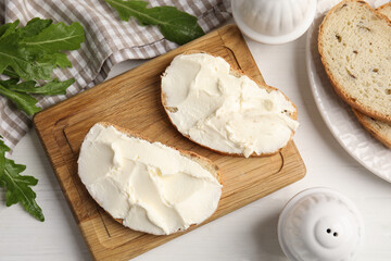 Bread with cream cheese on white wooden table, flat lay