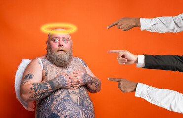 Fat afraid man with beard ,tattoos and wings acts like an angel