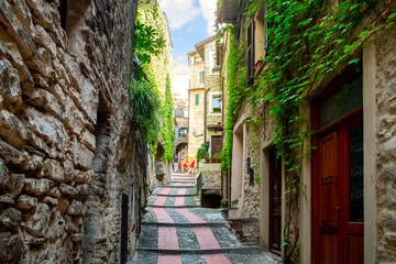 Tourists including a young couple walk up the narrow street path in the medieval village of Dolceacqua, Italy
