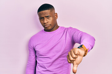 Young black man wearing casual pink sweater looking unhappy and angry showing rejection and negative with thumbs down gesture. bad expression.