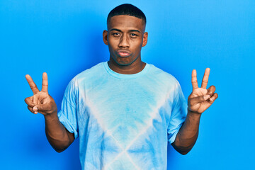 Young black man doing victory sign and peace gesture looking at the camera blowing a kiss being lovely and sexy. love expression.