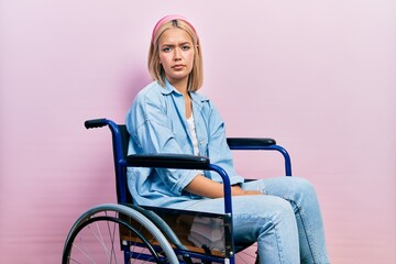 Beautiful blonde woman sitting on wheelchair depressed and worry for distress, crying angry and afraid. sad expression.
