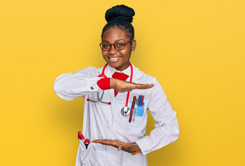 Young african american woman wearing doctor uniform and stethoscope gesturing with hands showing big and large size sign, measure symbol. smiling looking at the camera. measuring concept.