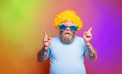 Fat thoughtful man with beard, tattoos and sunglasses dances music on a disco