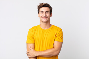 young handsome man laughing shyly and cheerfully, with a friendly and positive but insecure attitude