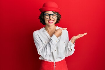Young brunette woman wearing stewardess style and glasses amazed and smiling to the camera while...