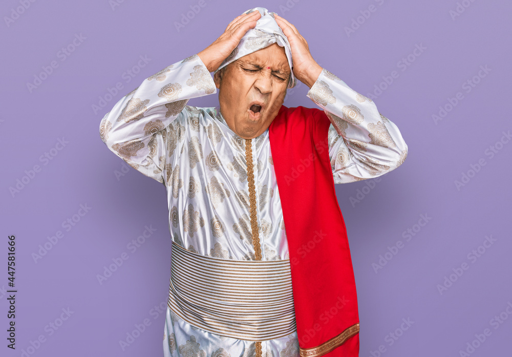 Wall mural Senior hispanic man wearing tradition sherwani saree clothes suffering from headache desperate and stressed because pain and migraine. hands on head.