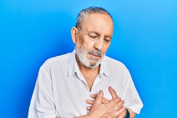 Handsome senior man with beard wearing casual white shirt smiling with hands on chest with closed eyes and grateful gesture on face. health concept.