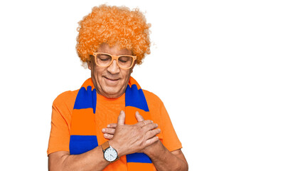 Senior hispanic man football hooligan cheering game smiling with hands on chest with closed eyes and grateful gesture on face. health concept.