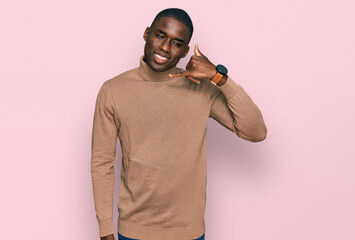 Young african american man wearing casual winter sweater smiling doing phone gesture with hand and fingers like talking on the telephone. communicating concepts.