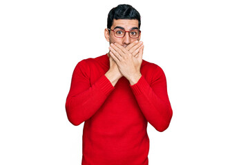 Handsome hispanic man wearing casual clothes and glasses shocked covering mouth with hands for...