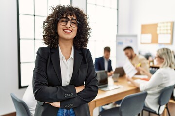 Young middle east businesswoman smiling happy standing with arms crossed gesture at the office during business meeting.