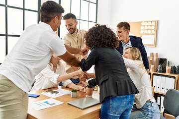 Group of business workers smiling happy celebrating making tower with fists together at the office.