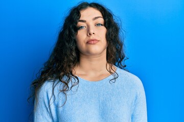 Young brunette woman with curly hair wearing casual clothes relaxed with serious expression on face. simple and natural looking at the camera.