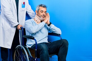 Handsome middle age man with grey hair on wheelchair wearing cervical collar sleeping tired dreaming and posing with hands together while smiling with closed eyes.