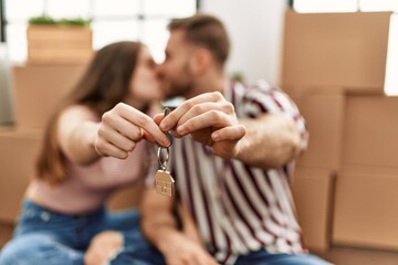 Young caucasian couple kissing and holding key of new home.