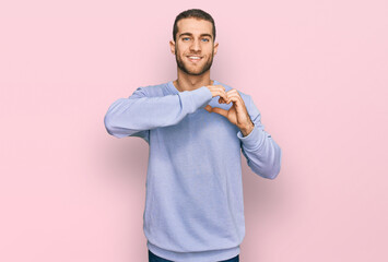 Young caucasian man wearing casual clothes smiling in love doing heart symbol shape with hands. romantic concept.