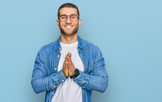 Young caucasian man wearing casual clothes praying with hands together asking for forgiveness smiling confident.