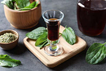 Glass of broadleaf plantain tincture on grey table