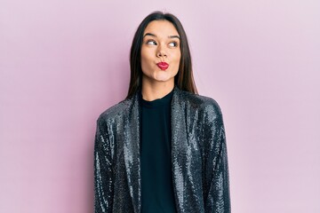 Fototapeta premium Young hispanic girl wearing party jacket smiling looking to the side and staring away thinking.