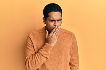 Obraz premium Young handsome hispanic man wearing casual winter sweater bored yawning tired covering mouth with hand. restless and sleepiness.