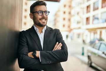 Young hispanic businessman with arms crossed smiling happy at the city.