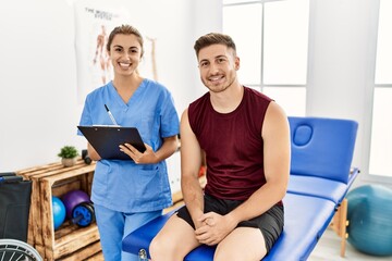 Young hispanic physioterapist woman explain diagnosis to patient man at the clinic.