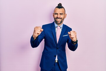 Young hispanic man wearing business suit and tie angry and mad raising fists frustrated and furious while shouting with anger. rage and aggressive concept.