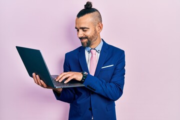 Young hispanic man working using computer laptop looking positive and happy standing and smiling with a confident smile showing teeth