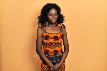 Young african american woman wearing traditional african clothes skeptic and nervous, frowning...